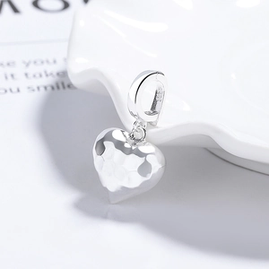 Minimalist S925 sterling silver heart pendant with hammered texture on white ceramic dish