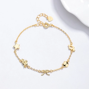 Bracelet en argent 925 doré avec breloques étoile et nœud sur une surface blanche