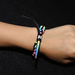 Detailed shot of rainbow braided bracelet with black Gemini slider on wrist