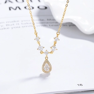 Elegant gold 925 silver necklace featuring a teardrop zircon pendant on white book