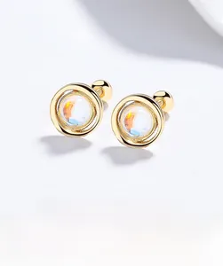 Macro detail of round moonstone earrings with golden threaded backing and iridescent glow