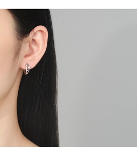 Détail de créoles en argent sterling 925 avec motif étoile portées par un mannequin