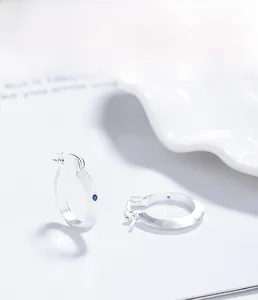 Macro detail of S925 sterling silver brushed hoop earring with a blue zircon stone
