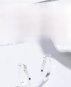 Detail of 925 sterling silver hoop earrings with a small round blue zircon stone inlay