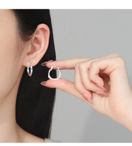 Detail of matte brushed silver hoop earring featuring a tiny blue sapphire accent