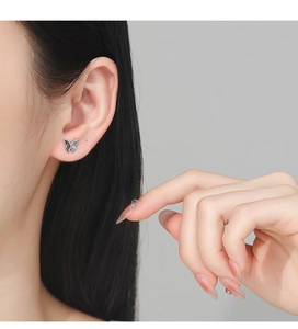 Detailed close-up of a 925 silver butterfly stud earring with black crystal inlay on ear
