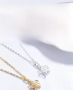 Detailed macro view of S925 silver flower pendants with zircons in gold and silver finish