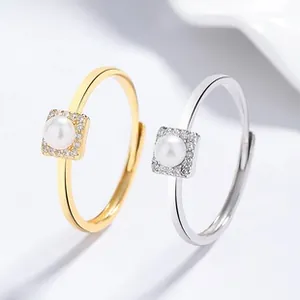 Detail of square zircon micro-pave setting with freshwater pearl on dual-tone open rings