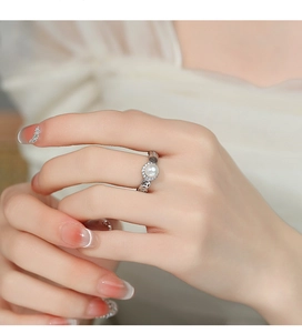 Détail d'une bague élégante en argent 925 avec perle, halo de zircons et motif de pièce