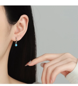 Dettaglio macro di un orecchino in argento 925 con pietra turchese indossato da una modella