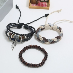 Ensemble de trois bracelets rétro en cuir avec pendentif plume et perles en bois sur fond blanc