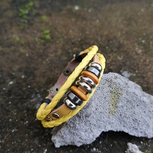Detail of yellow woven leather bracelet with wooden beads and silver metal rings