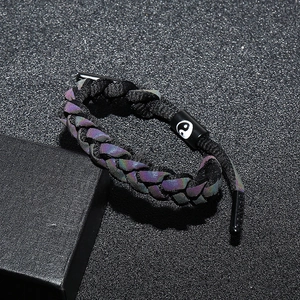 Vue macro du bracelet tressé réfléchissant avec breloque Tai Chi Yin Yang et logo gravé