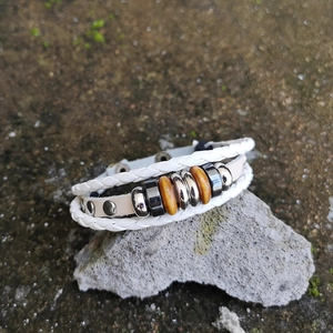 Detail of bohemian multilayer braided leather bracelet with beads on a grey stone