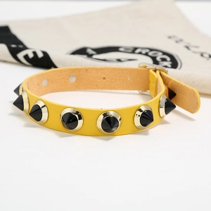 Detail of yellow leather punk choker with black spikes and gold metal accents