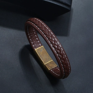 Detail of dark brown braided leather bracelet with vintage brass clasp and stitching