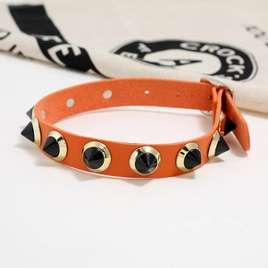 Detail of orange leather punk choker with black conical spikes and silver buckle