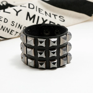 Detail of punk wide black leather bracelet with three rows of silver pyramid metal studs
