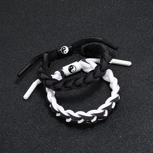 Détail de bracelets tressés pour couple avec breloques yin yang tai chi noir et blanc