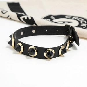 Detail of black leather punk choker featuring spiked rivets with gold-tone metal rims