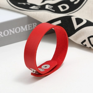 Close-up of bright red leather bracelet with silver snap buttons and textured edges
