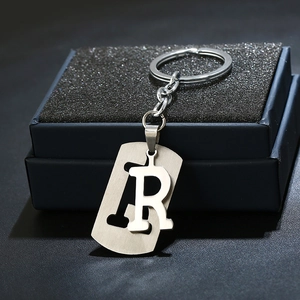 Detail of silver letter R keychain with brushed metal texture and double-layer design