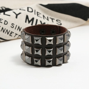 Detail of punk wide leather bracelet featuring three rows of metal square pyramid studs