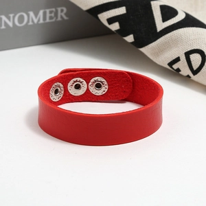 Detailed view of red leather adjustable bracelet featuring three silver metal snap buttons