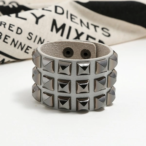 Detailed close-up of a punk leather bracelet with three rows of pyramid metal studs