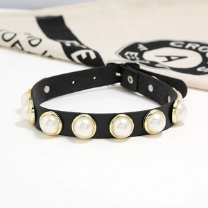 Dettaglio del choker in pelle nera con perle bianche e bordi dorati