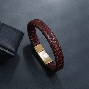 Gros plan d'un bracelet en cuir tressé rouge foncé avec fermoir en laiton mat rétro