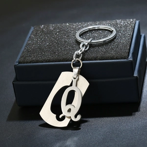 Detail of a polished stainless steel letter Q keychain pendant on a premium black display box