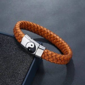 Detail of vintage braided brown leather bracelet with Tai Chi Yin Yang clasp on a jewelry box