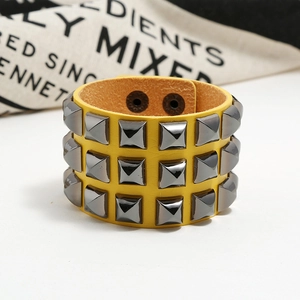 Macro view of punk yellow leather bracelet with three rows of square metal studs