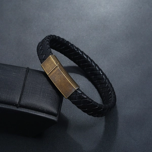 Détail d'un bracelet en cuir tressé noir avec fermoir magnétique en laiton vintage sur boîte