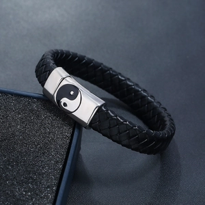 Braided leather bracelet with stainless steel yin yang magnetic clasp on grey cushion