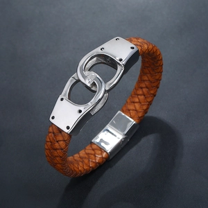 Macro shot of brown braided leather bracelet featuring silver handcuff metal detail