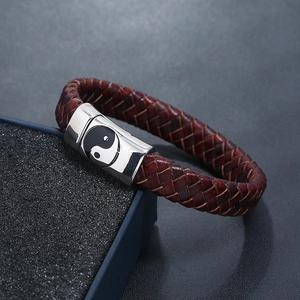 Macro shot of dark red braided leather bracelet with Tai Chi Yin Yang symbol metal clasp