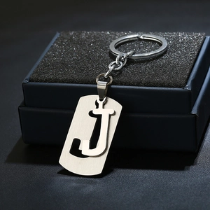 Macro shot of minimalist silver metal letter J keychain on black display box