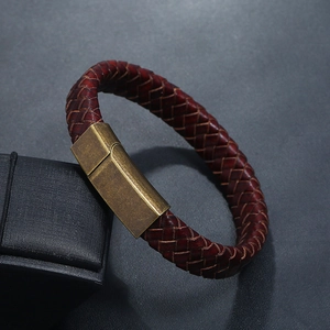 Gros plan d'un bracelet en cuir tressé bordeaux avec un fermoir magnétique en bronze poli