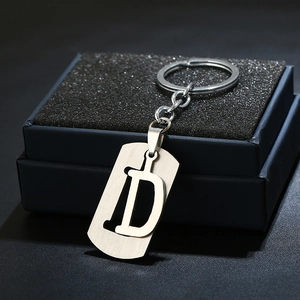 Polished stainless steel letter D keychain on a dark gift box with metallic luster