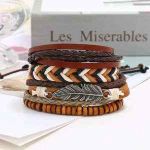 Dettaglio di braccialetti in pelle vintage multistrato con ciondolo a piuma e perle in legno