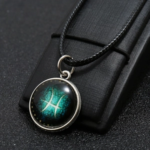 Macro shot of a Pisces zodiac pendant featuring a blue galaxy background on a display stand