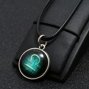 Detail of Libra zodiac pendant featuring luminous constellation on black textured surface