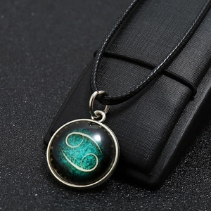 Macro shot of Cancer zodiac glowing pendant with silver metal base and black cord
