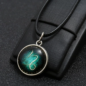 Macro view of Capricorn zodiac necklace with glowing nebula glass gem and bronze base