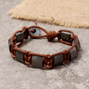 Retro braided leather bracelet for men with gray metallic beads on a stone background