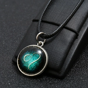 Close-up of a luminous blue heart glass pendant on a black leather display stand