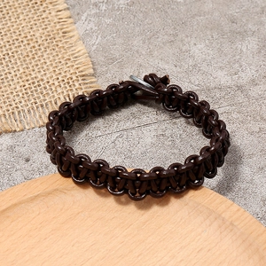 Bracelet rétro en cuir tressé marron pour homme avec fermoir en métal sur fond pierre