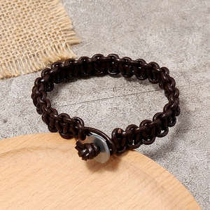 Bracelet vintage en cuir tressé marron avec fermoir disque en métal sur fond rustique